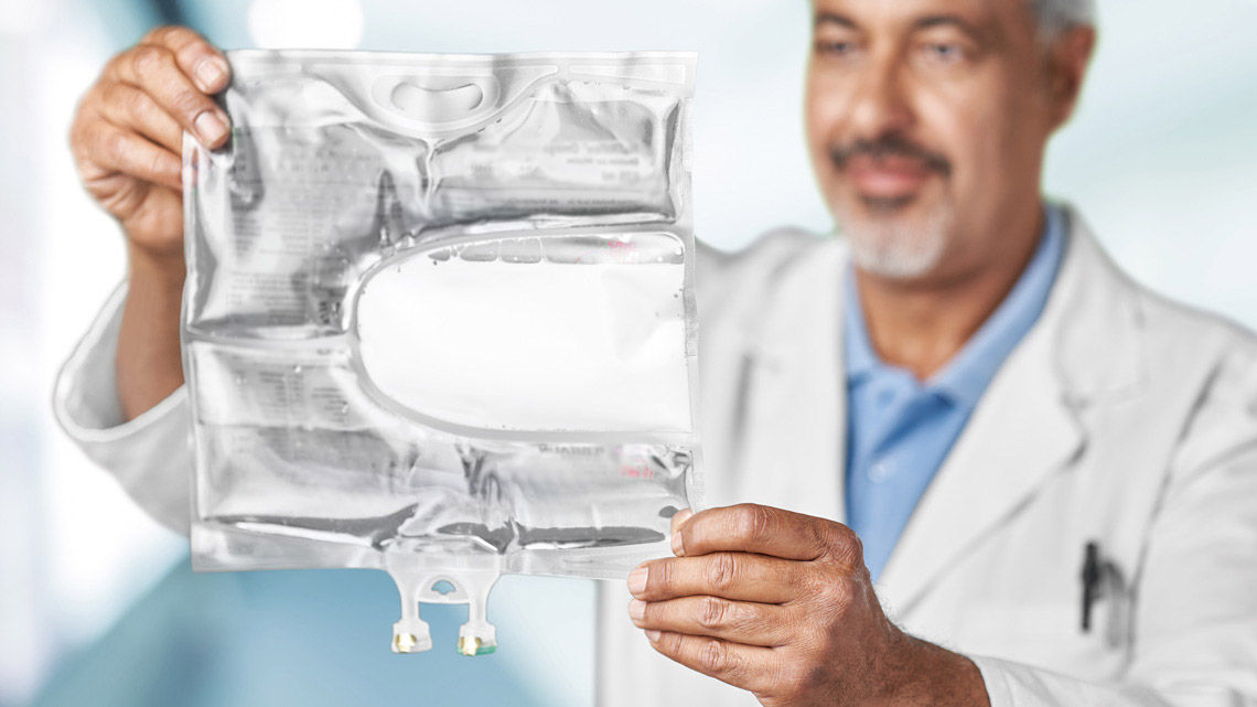 A male healthcare professional is holding a 3-chamber bag