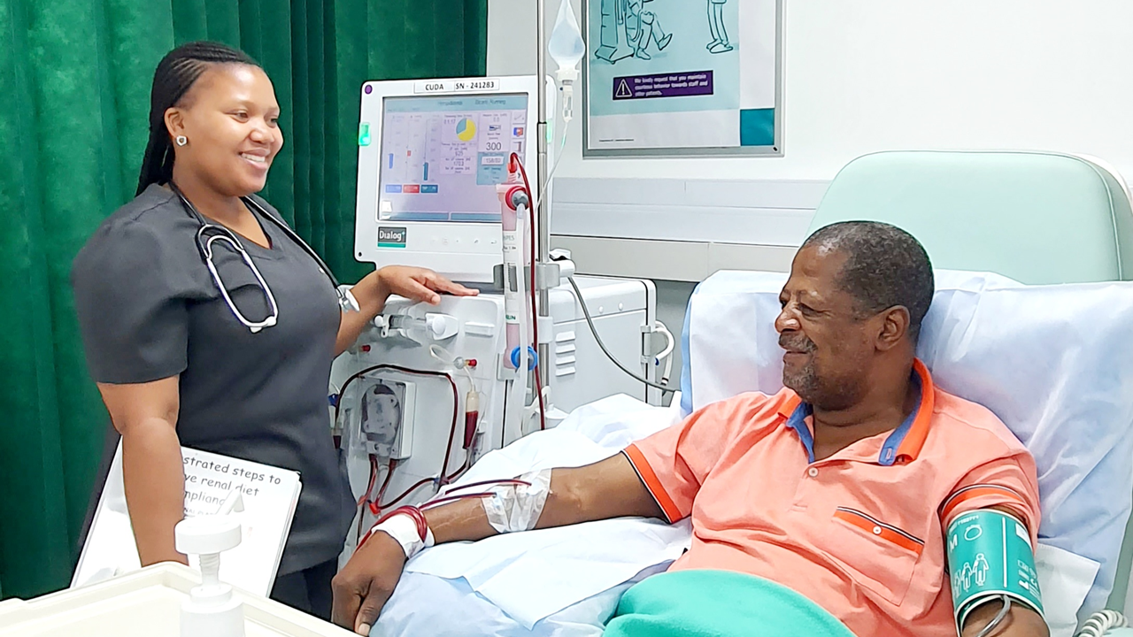Patient gets dialysis, in the background a nurse handling a dialog + machine