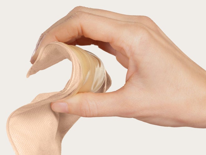Hand presses the wafer of a soft convex stoma bag to demonstrate its flexibility