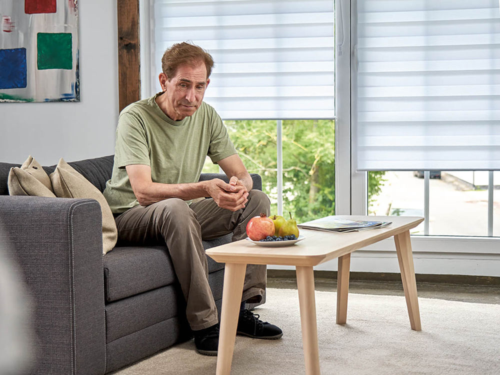 Elderly man sitting thoughtfully on a couch in the living room