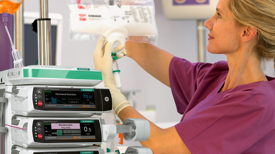 A female healthcare professional is adjusting the infusion pumps