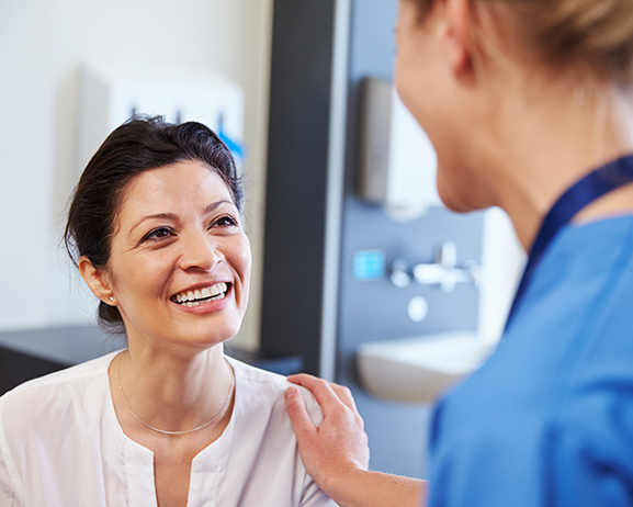 Female Patient Being Reassured By Doctor In Hospital Room