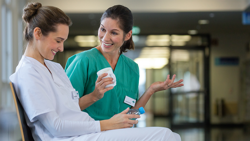 Two female health care workers have fun in hospital hallway