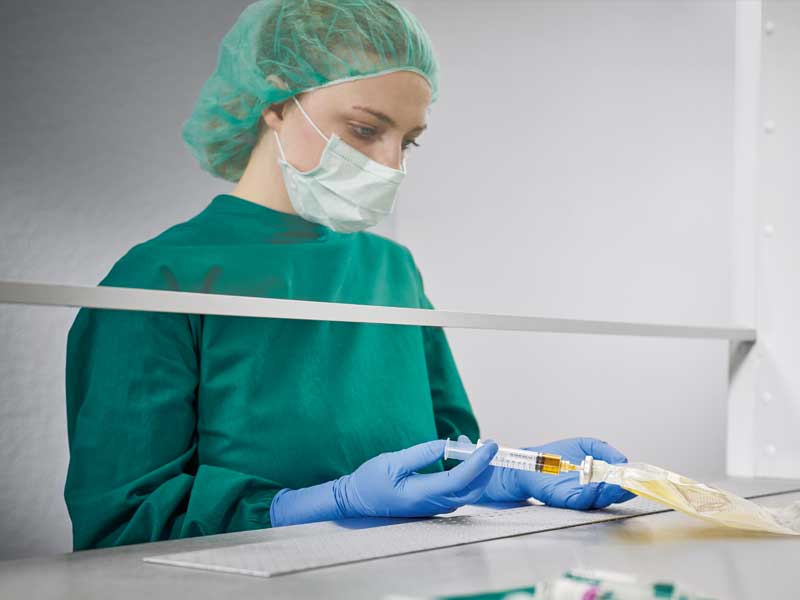 A nurse sits with her patient in a home environment with a tablet in her hand and they talk with each other. In the foreground are nutricomp bottles and fruit on a table