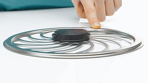 A hand is touching a wheel-formed metal object, which might be part of a medical device or equipment