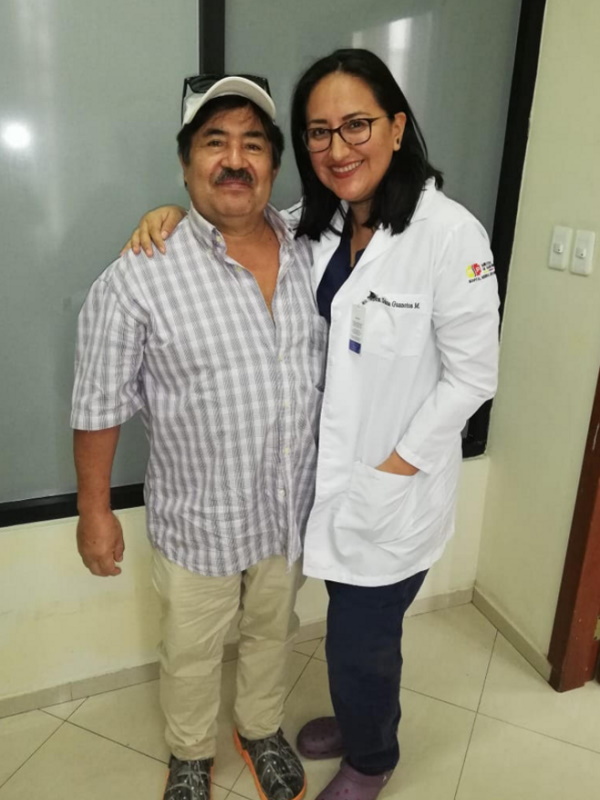 A man stands next to his doctor, both smile into the camera