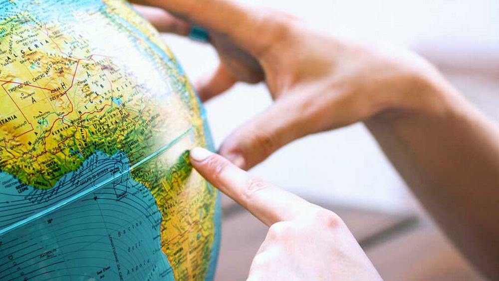 a finger pointing to a specific location on a globe