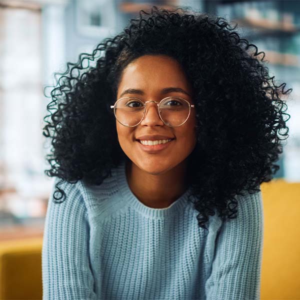 An individual wearing glasses against a green background, exuding confidence and intelligence. 