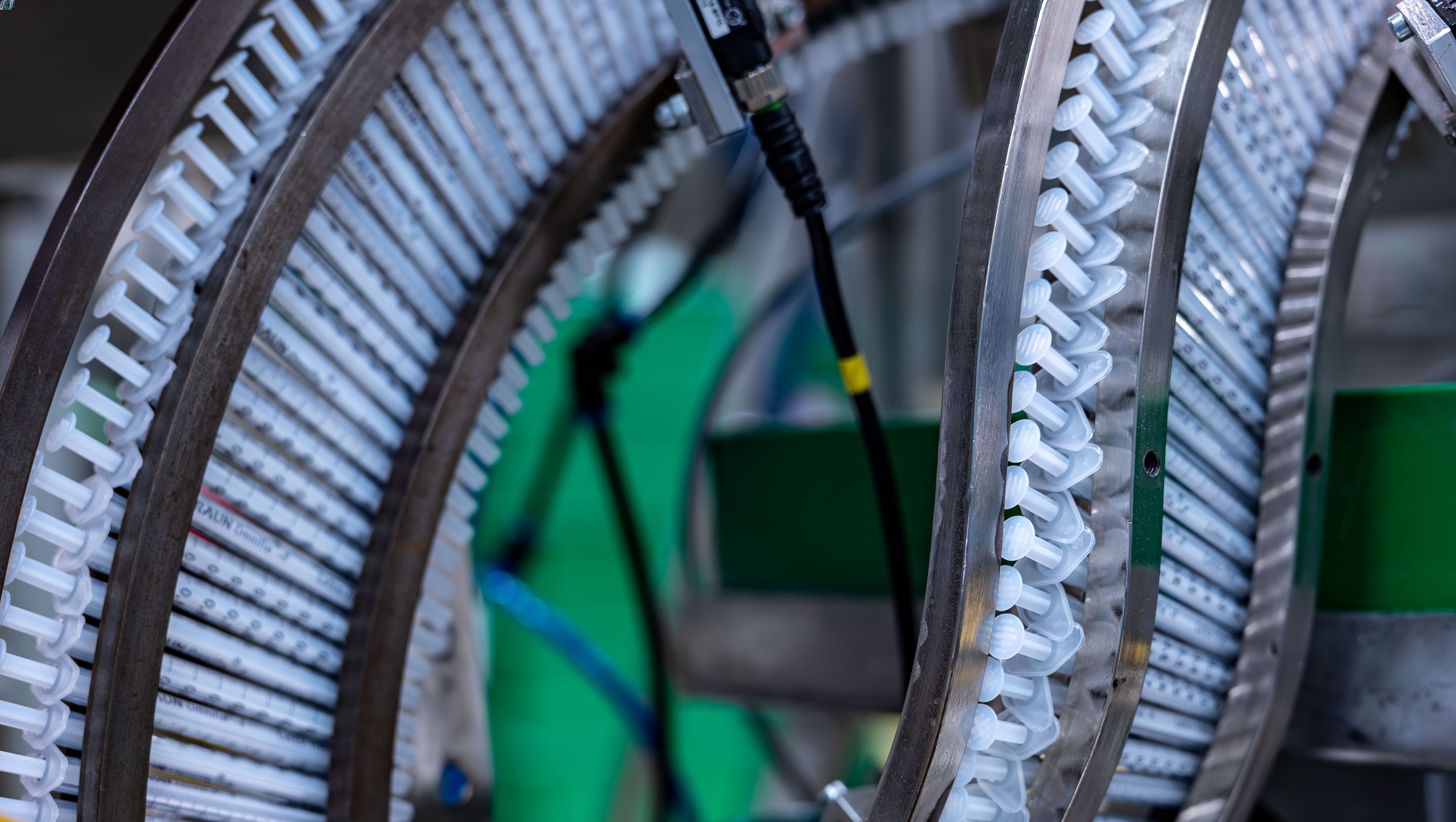 Many syringes in a row in production environment. It symbolises our analysis of the product life cycle in order to determine the total environmental impact of a product from supply of the raw materials to disposal. 